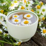 Organic chamomile tea with chamomile flowers next to cup