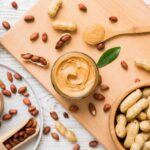 Organic nut butter in jar with nuts surrounding it