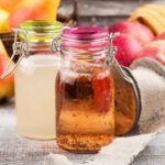 Difference between apple cider vinegar and white vinegar next to apples and pears