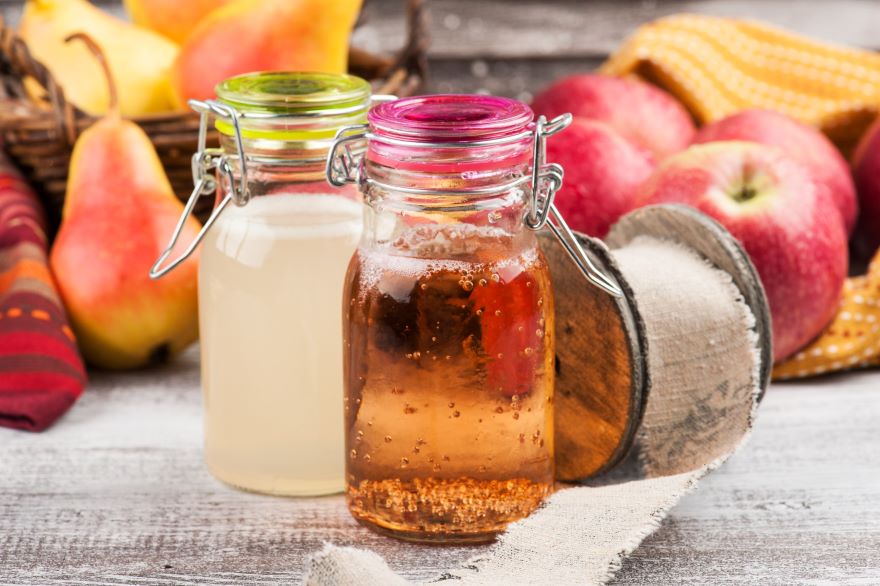 Difference between apple cider vinegar and white vinegar next to apples and pears