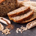 Superfood bread sliced next to different grains