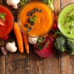 Superfood soup in three bowls next to vegetables