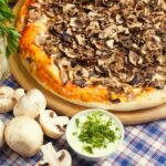 Mushrooms for pizza with vegetables on wooden background
