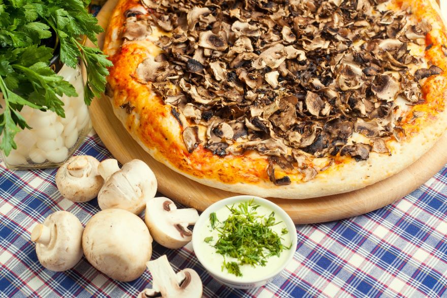 Mushrooms for pizza with vegetables on wooden background