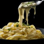 Dairy-free Alfredo sauce dripping off a spoon onto linguine