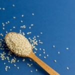 Are sesame seeds gluten-free? on a spoon on blue background