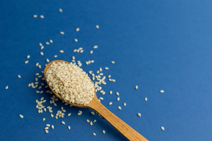 Are sesame seeds gluten-free? on a spoon on blue background