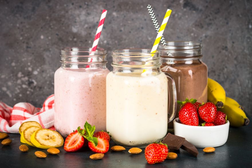 Dairy-free protein shakes next to strawberries, nuts