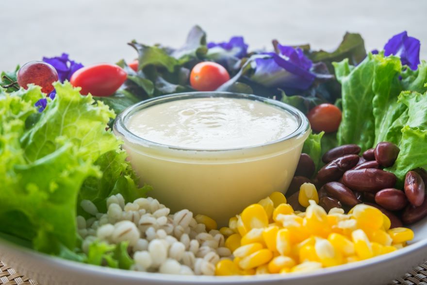 Dairy-free salad dressing in the middle of plate of salad