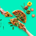 Gluten-free dairy-free pizza with hands taking a slice each