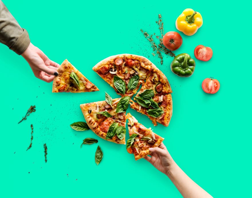 Gluten-free dairy-free pizza with hands taking a slice each