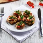 Gluten-free stuffed mushrooms on white plate with knife and fork