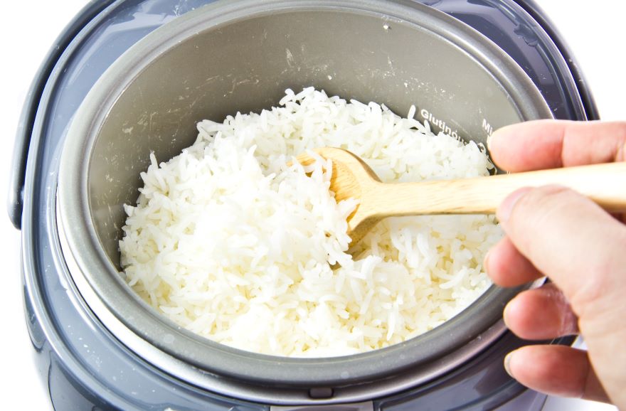 Best rice cookers with rice being cooked with wooden spoon in cooker