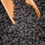 Black chickpeas running off a wooden spatula