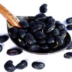 Black turtle beans in a spoon on a white background