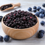 Dehydrated blueberries in a bowl with fresh blueberries next to it