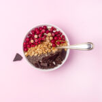 Chia Seed Breakfast Bowl with berries and a spoon in bowl on pink background