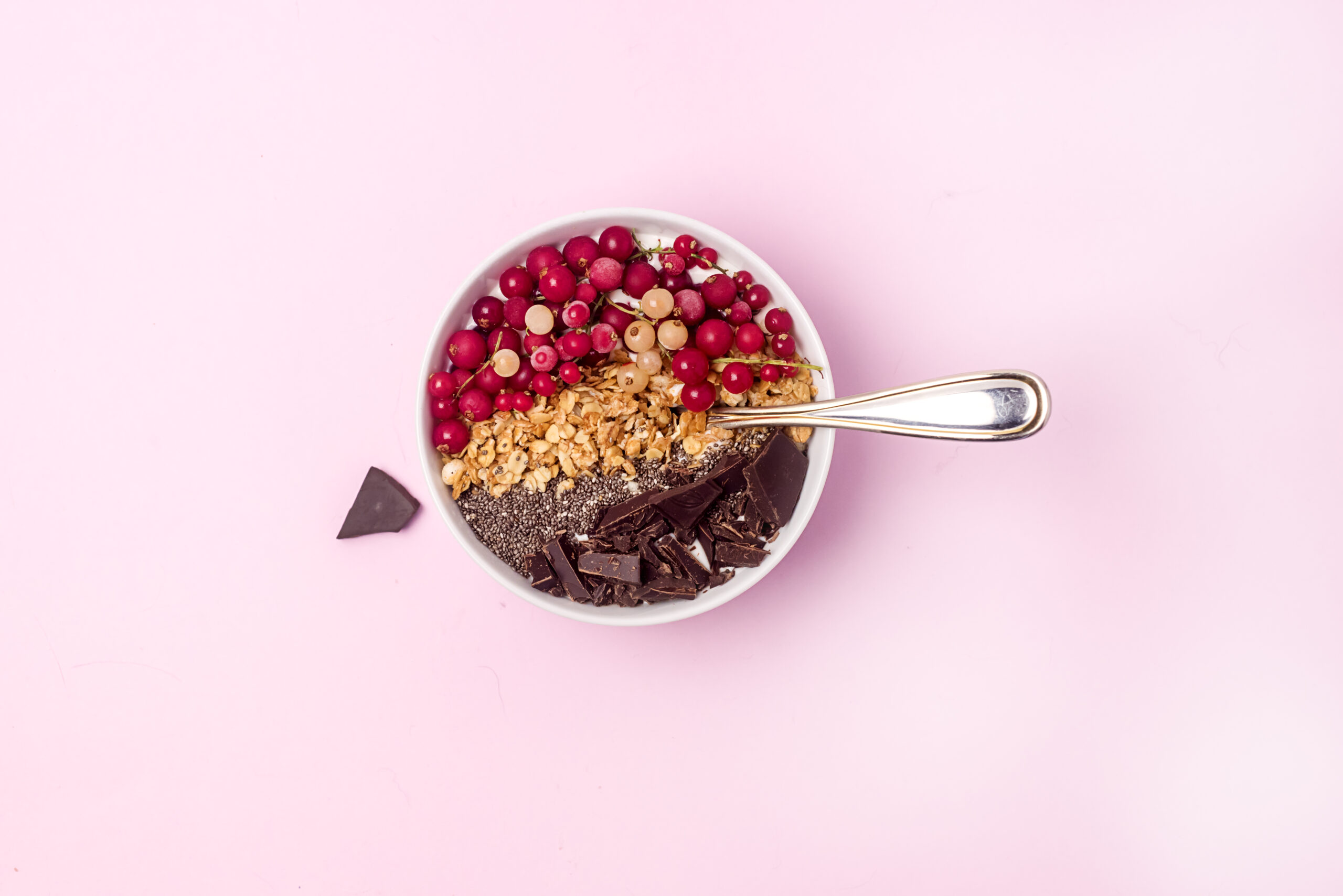 Chia Seed Breakfast Bowl with berries and a spoon in bowl on pink background