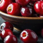 Cranberries fresh in a bowl with loose cranberries beside it