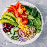 Rainbow veggie-packed quinoa salad with lemon-tahini dressing on a white plate