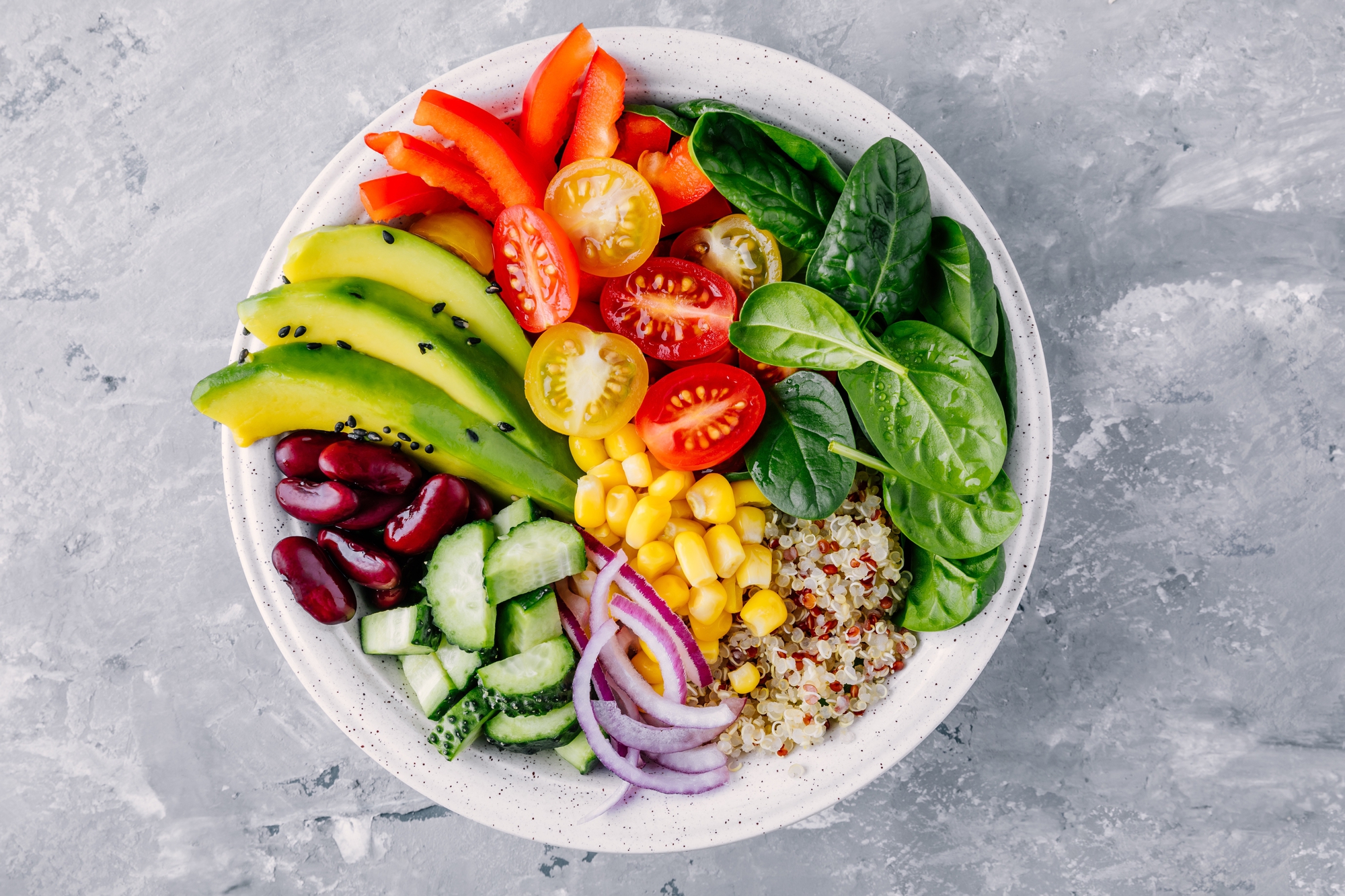 Rainbow veggie-packed quinoa salad with lemon-tahini dressing on a white plate