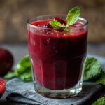 Beet and berry antioxidant power juice in a glass with mint on top