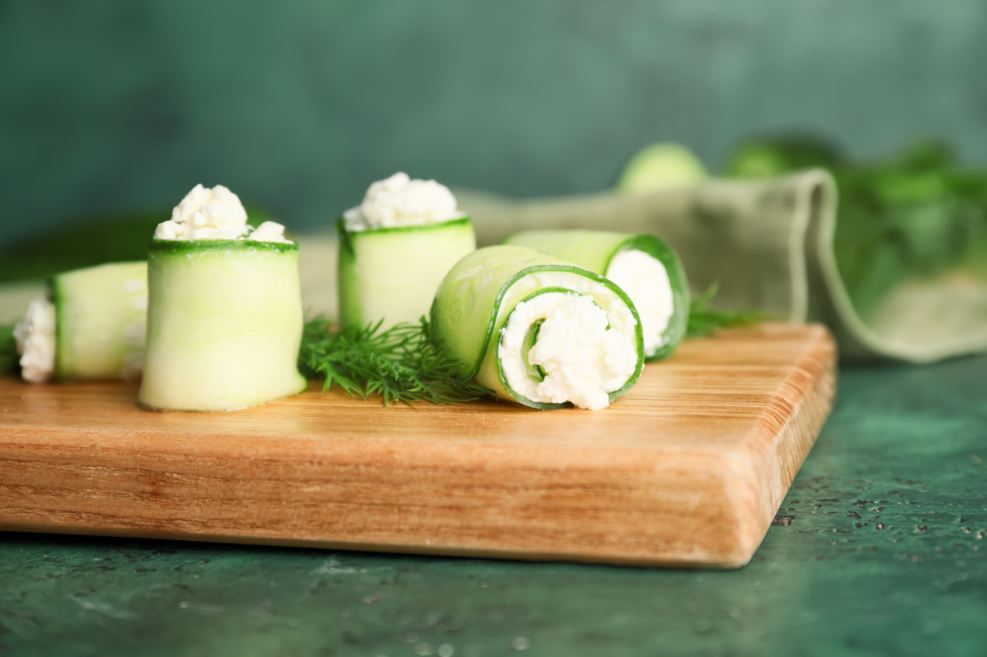 Cucumber rolls with hummus and fresh herb filling on a board