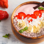 Kefir berry blast smoothie bowl next to two strawberries