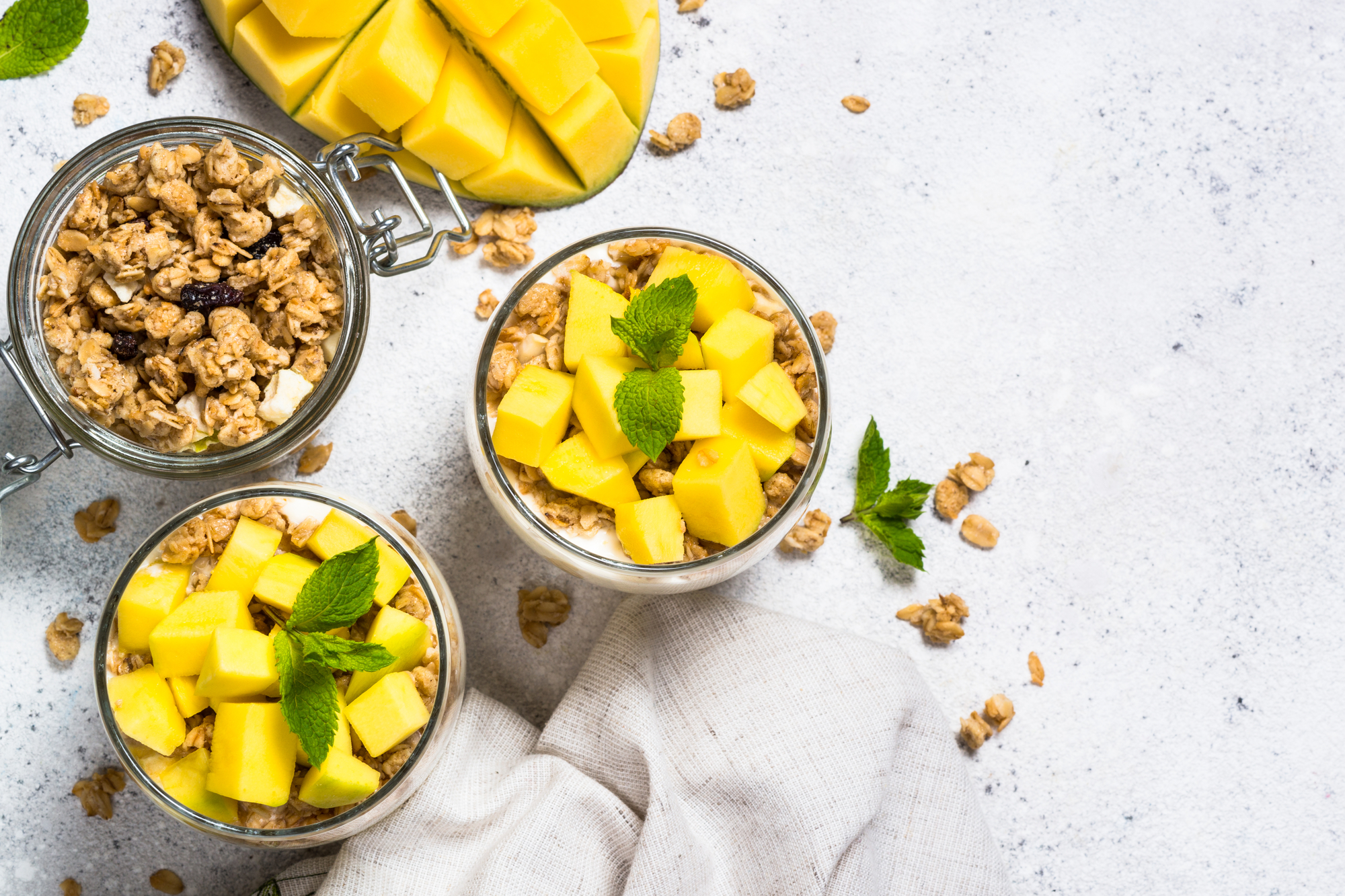 Tropical coconut oil granola with mango and macadamia nuts with two bols next to mango