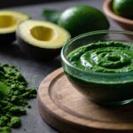 Vibrant green spirulina and chlorella superfood pesto next to a halved avocado